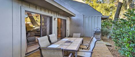 Un patio exterior con una mesa, sillas, una puerta corrediza de vidrio y una parrilla.