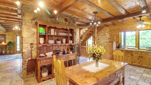 A rustic wooden interior with a dining table, wooden cabinets, and a stone wall.