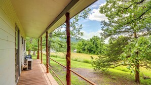 A wooden deck with a view of a grassy field and trees. - Ozark Escapes Cabin! Serene Forest & Mtn Setting (Harrison)