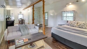 A modern, well-lit room with a large bed, a sofa, and a dining area. - Ozark Escapes Cabin! Serene Forest & Mtn Setting (Harrison)