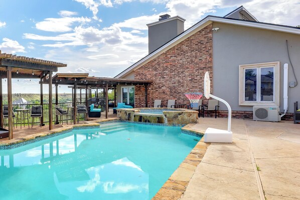 Un jardín trasero con piscina, mobiliario de patio y una zona cubierta.