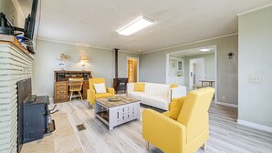Un salon avec un canapé blanc, des fauteuils jaunes, une table basse et une cheminée.