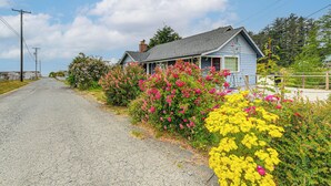 Une maison avec un porche, entourée d’arbustes en fleurs.