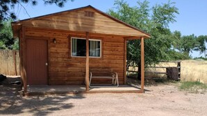 A wooden cabin with a single door, a window, and a porch.