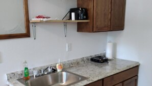 A kitchen with wooden cabinets, a granite countertop, a stainless steel sink, and a microwave.