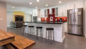 A modern kitchen with a central island, stainless steel appliances, and a bar stool seating area. - Delray Beach Tropical Retreat (Delray Beach)