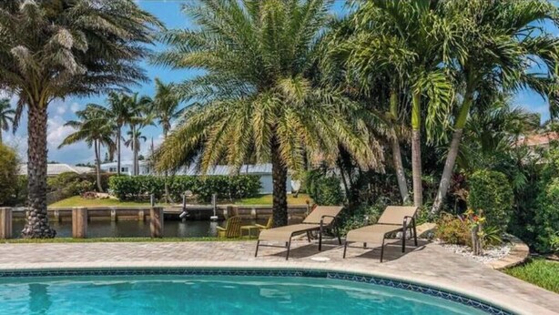 A swimming pool with lounge chairs and palm trees. - Delray Beach Tropical Retreat (Delray Beach)
