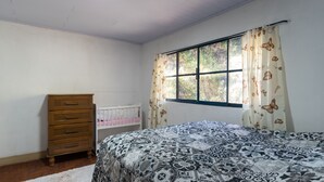 Un dormitorio con cama, cómoda, ventana con cortinas y cuna.