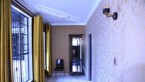 A hotel corridor with a view to a balcony, a toilet, and a wall-mounted light fixture. - 12-bedroom bed guest house in charming Bedfordvew with WiFi, AC (Germiston)