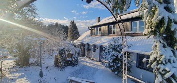 A snow-covered house with a wooden exterior, a visible garage, and a clear sky.