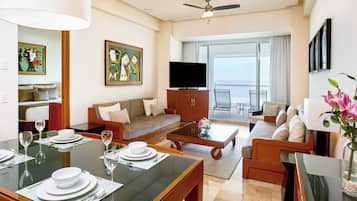 Una habitación de hotel moderna con comedor, sala de estar y balcón con vistas.