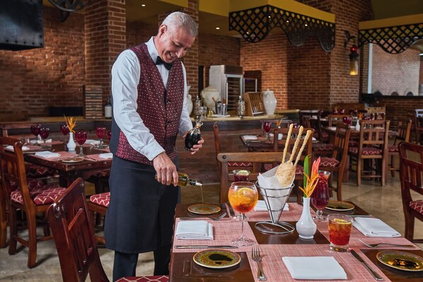Un restaurante con paredes de ladrillo, mesas de madera y sillas rojas acolchadas.