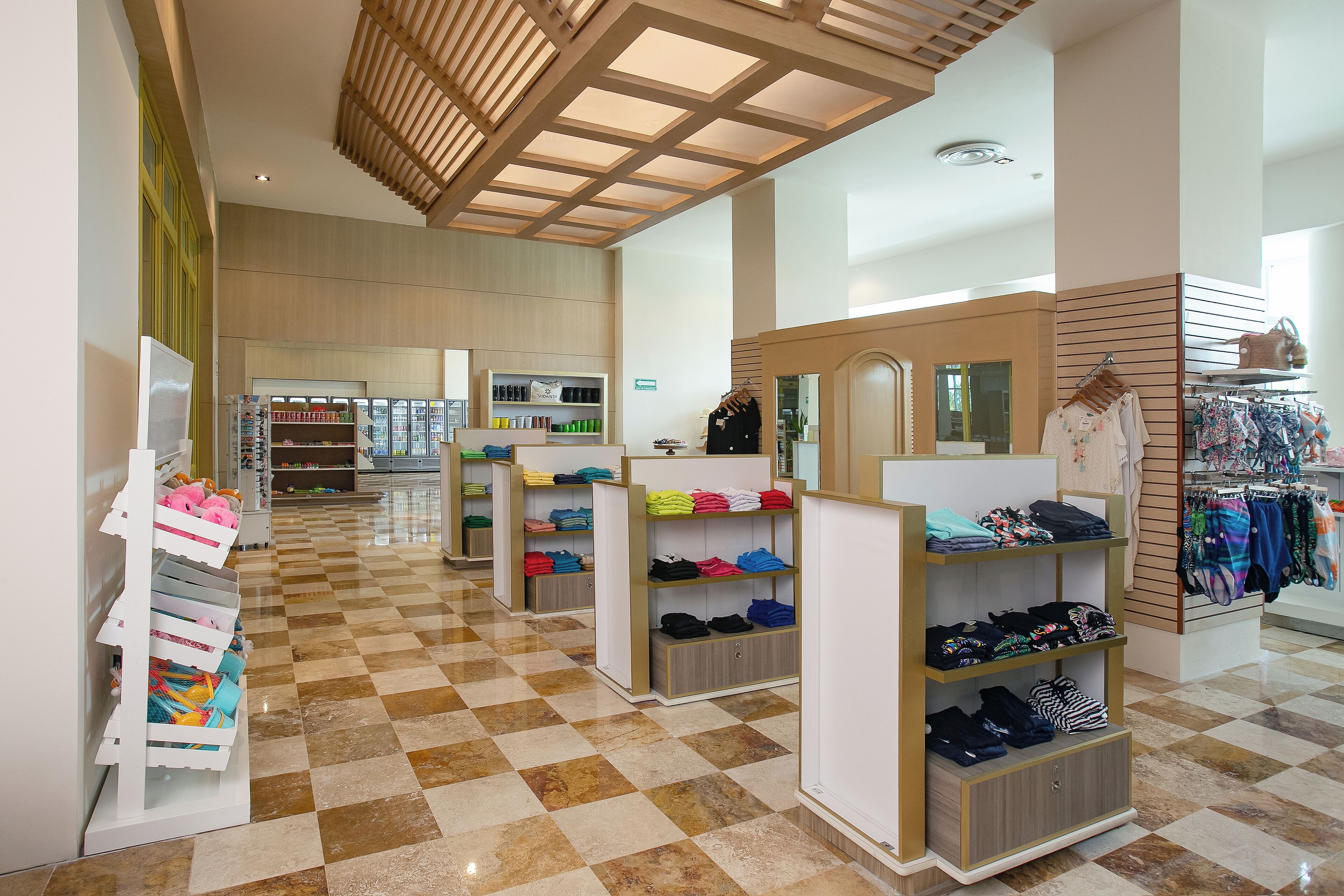 A spacious retail store with checkered flooring, organized shelves of folded clothing, and a wooden ceiling design.