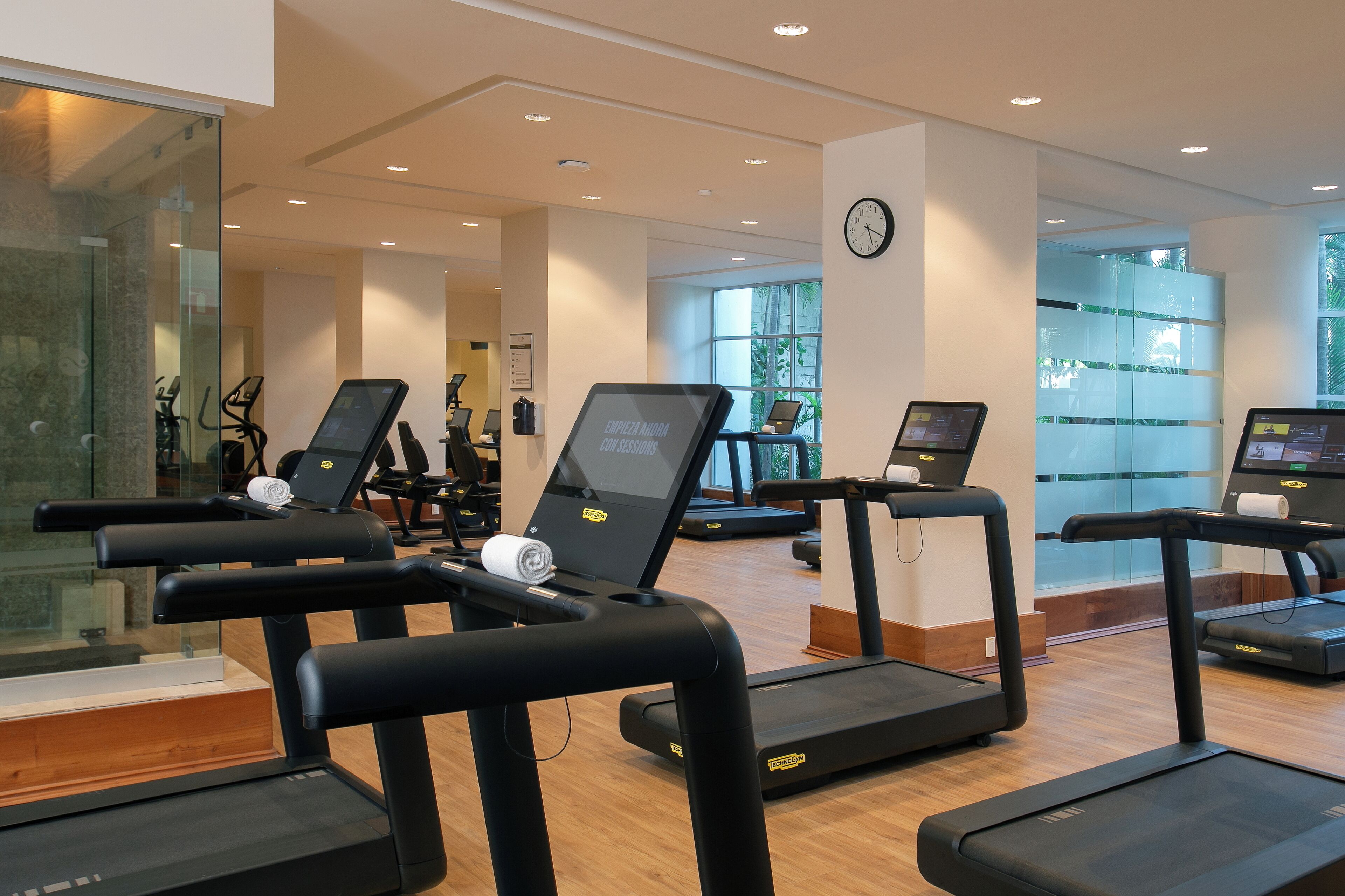 A gym with treadmills, exercise bikes, and a digital kiosk.