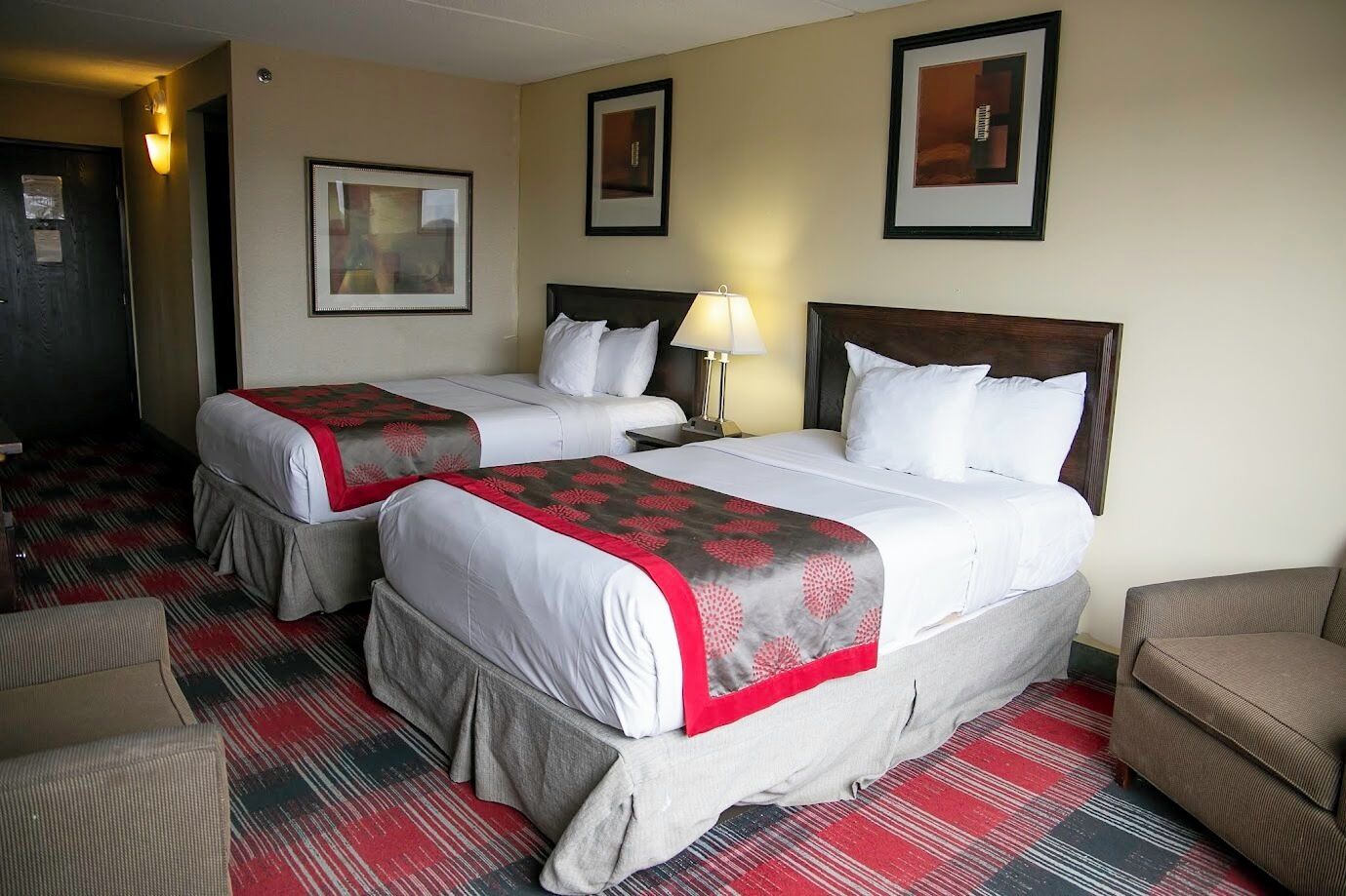 Een hotelkamer met twee bedden, een bank, een lamp en een vloerbedekking.