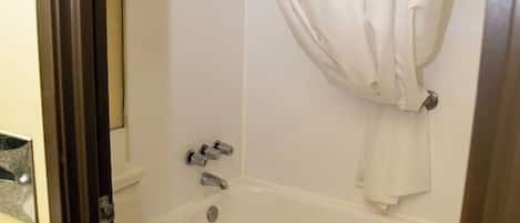 Un baño con bañera, inodoro y cortina de ducha.