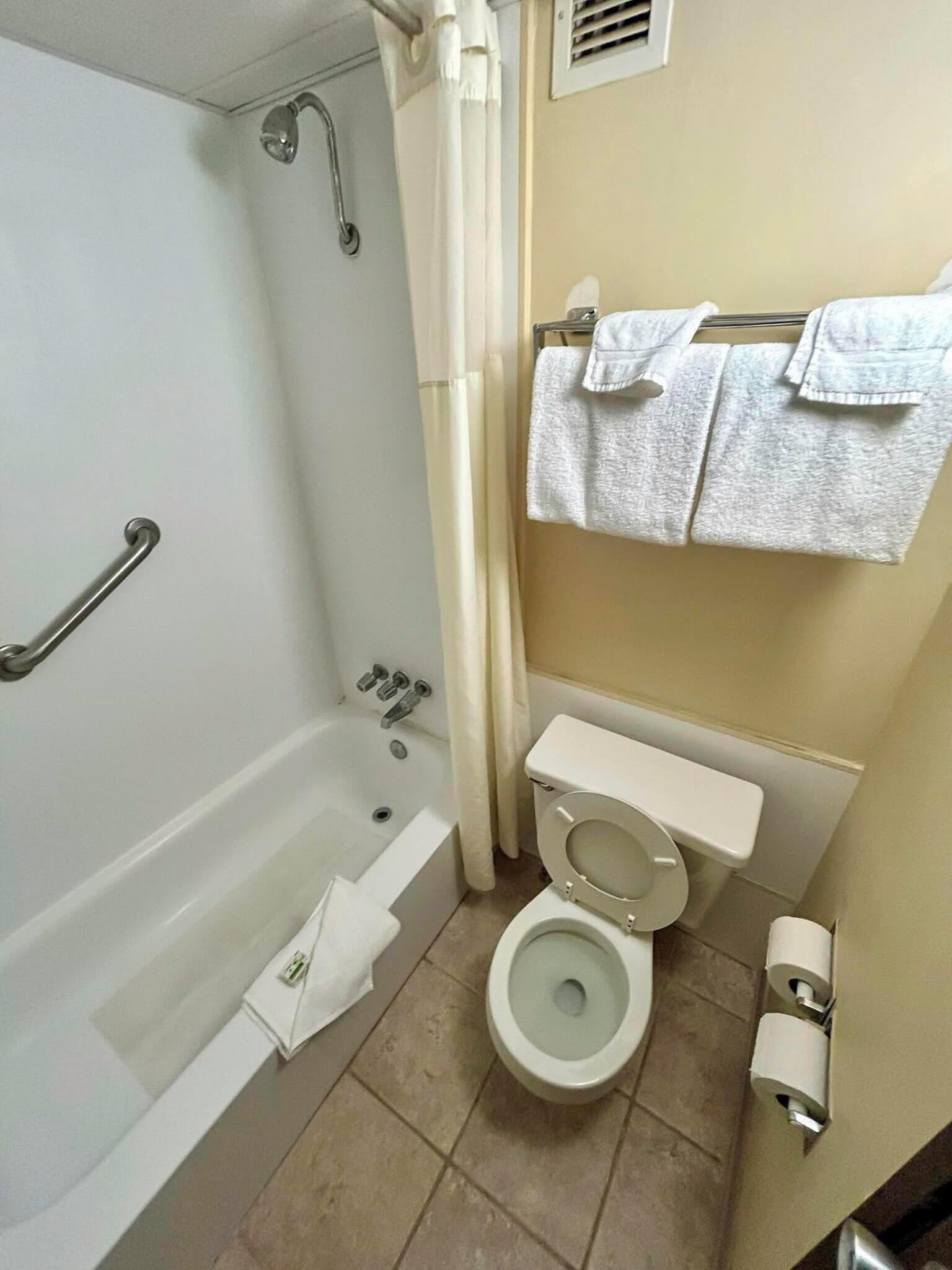 A bathroom with a bathtub, toilet, and towel rack.