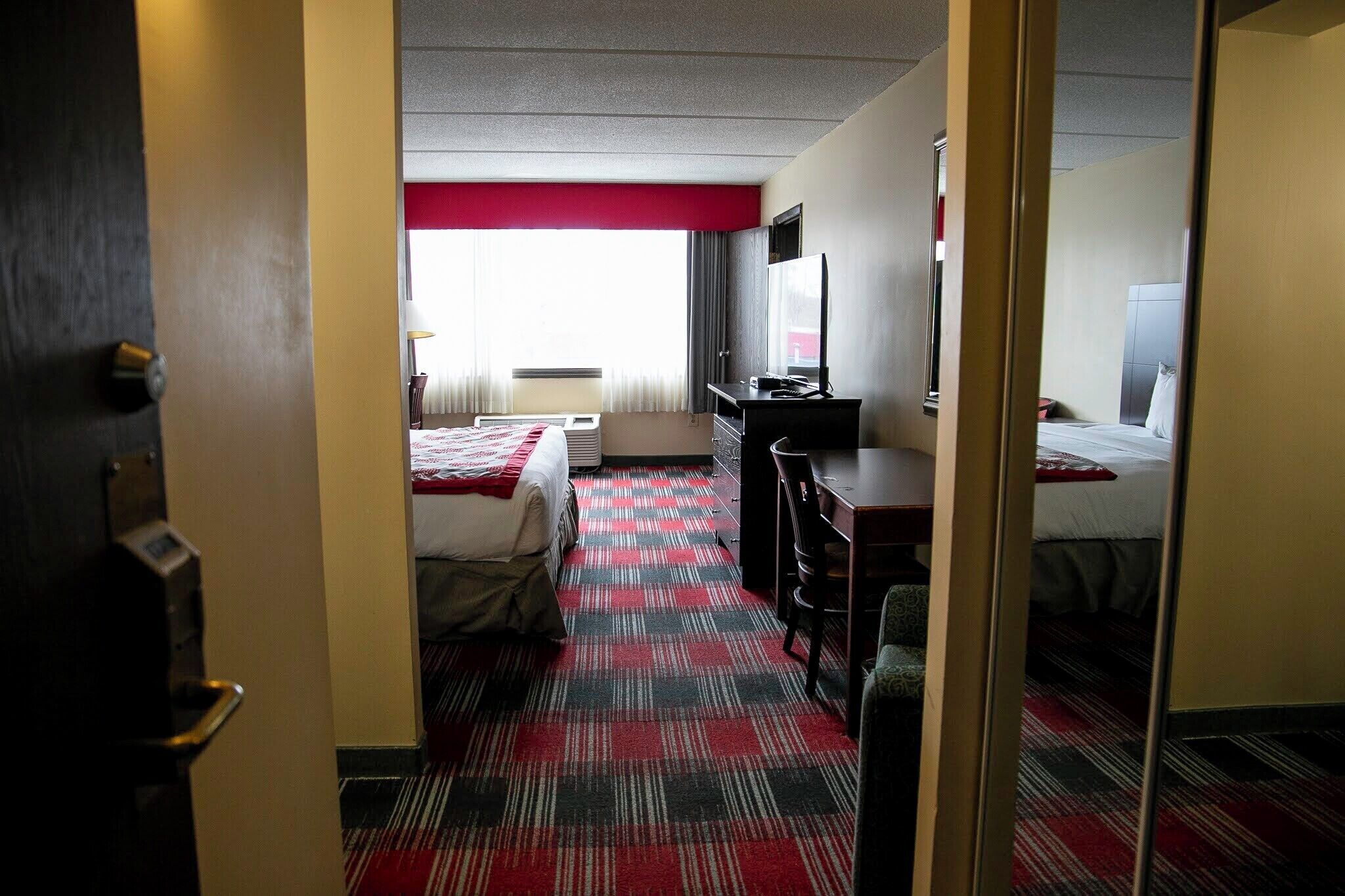 Een hotelkamer met een bed, een bureau, een stoel en een televisie.