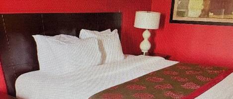 A hotel room with a bed, a nightstand, a lamp, and framed pictures on the wall.
