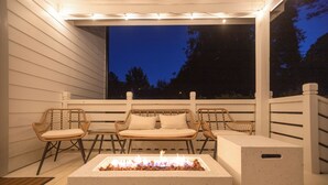 Un patio al aire libre con una chimenea, mobiliario de mimbre y vistas al cielo nocturno.