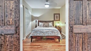 Une chambre à coucher avec un lit en bois, une table de chevet, une lampe et un ventilateur de plafond.