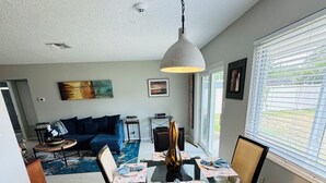 A dining area with a glass table, black chairs, and a pendant light. - Entire place in the heart of Sarasota (Sarasota)