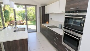 Eine moderne Küche mit Einbauofen, Spüle und großem Fenster mit Blick auf einen Garten.