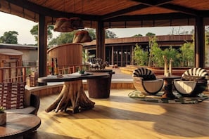 An outdoor seating area with round tables, wicker furniture, and a wooden deck.