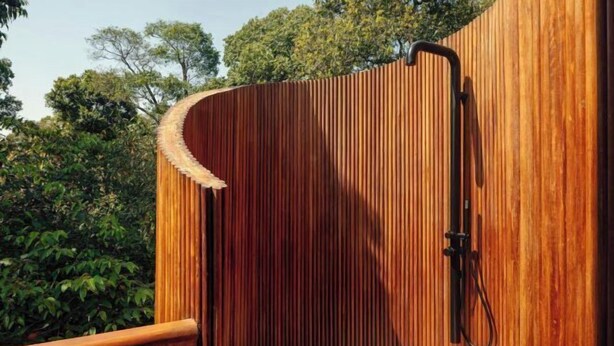 A wooden structure with a curved roof, a wooden railing, and a shower area. - The Ritz-Carlton, Masai Mara Safari Camp (MASAI MARA)