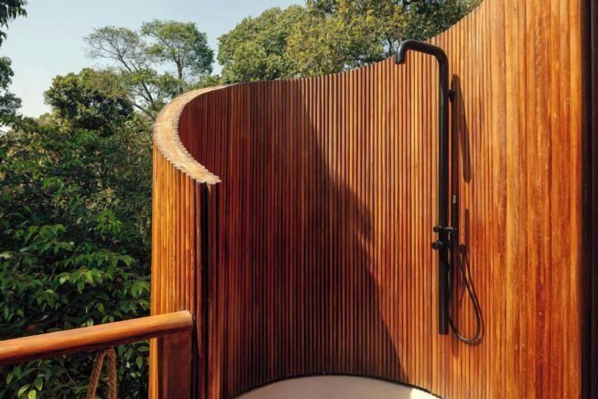 A wooden structure with a curved roof, a wooden railing, and a shower area.