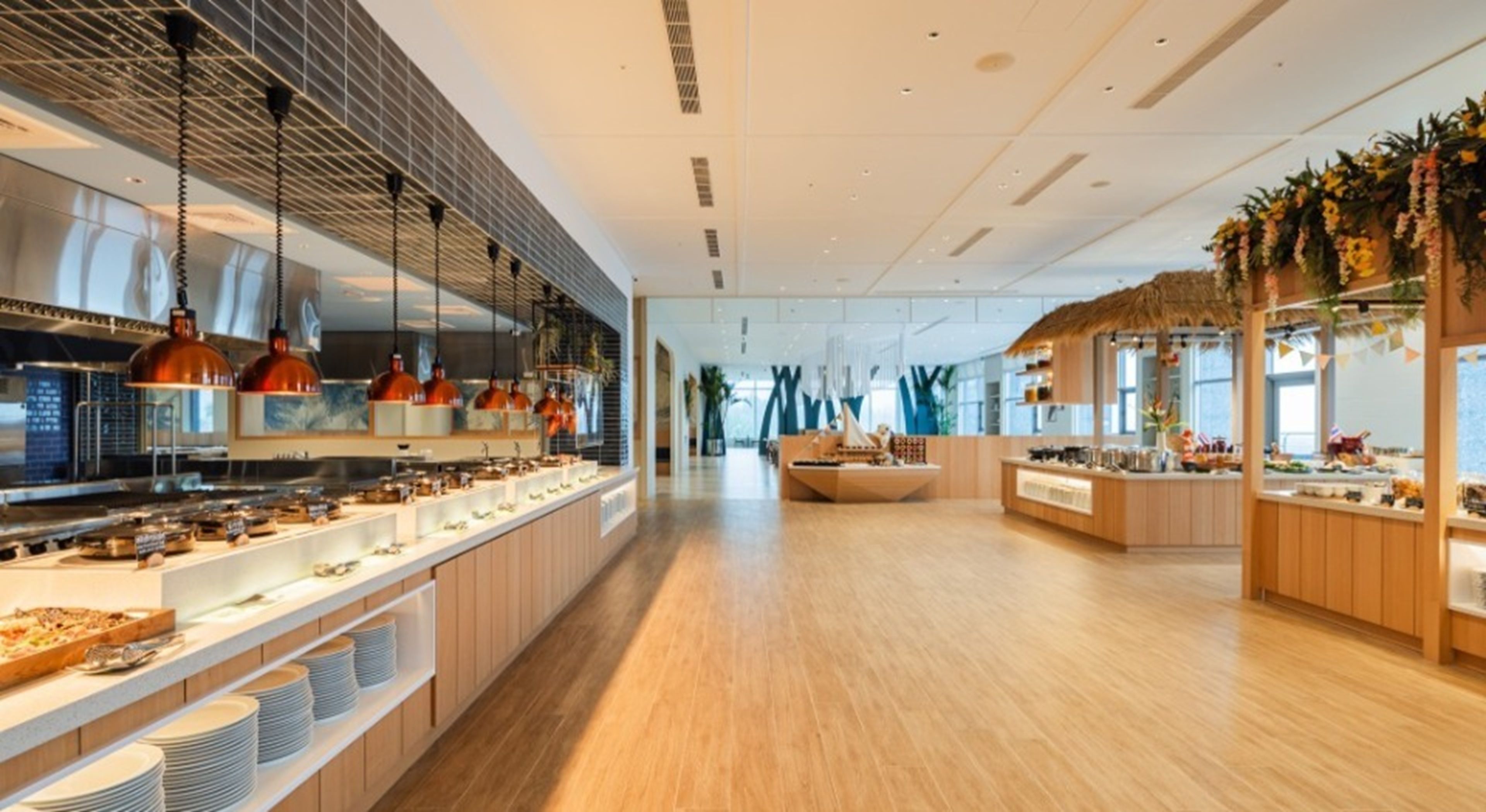 A modern restaurant with a long counter, pendant lighting, and a central seating area.