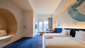 Habitación de hotel con una cama grande, una zona de estar con diseño curvo de madera y vistas a un paisaje nevado a través de la ventana.