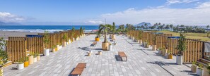 Una terrazza sul tetto con vista sulla spiaggia e sull'oceano, caratterizzata da ringhiere in legno, piante in vaso e zone relax.