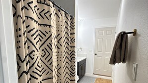 Une salle de bain avec un rideau de douche, un porte-serviettes et un plancher en bois.