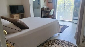 A bedroom with a bed, a TV, a desk, and a chair.