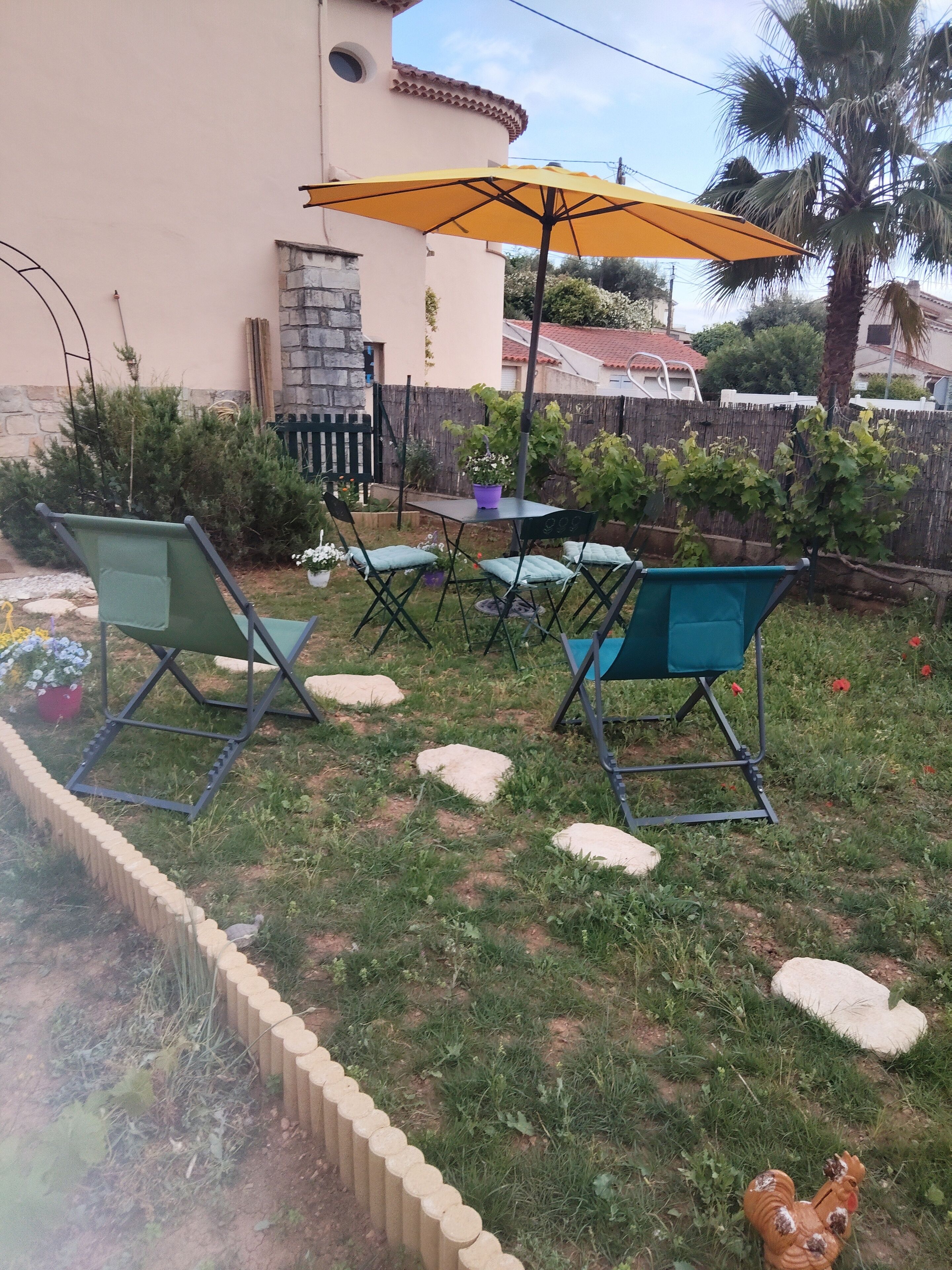 A patio with outdoor furniture, a yellow umbrella, and a stone wall.