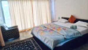 A bedroom with a bed, a chair, a window with curtains, and an air conditioning unit. - 
Perfect for couples, families, or friends. Book now and unwind in style! (panchgani)