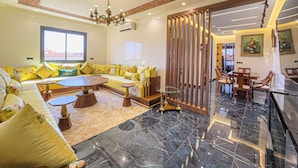 A spacious living area with a sofa set, a coffee table, and a dining table with chairs.