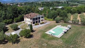Una casa de dos pisos con piscina y jardín.