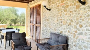 Une terrasse extérieure avec des murs en pierre, des meubles en bois et une vue sur les arbres.