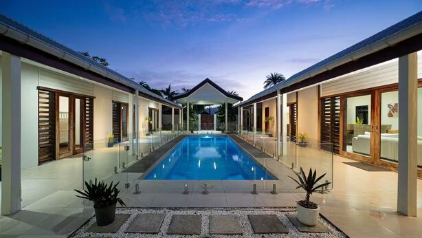 A modern pool area with a clear blue pool, surrounded by glass doors and potted plants. - Villa 100 - 4BR Private Villa w Private Pool - Fenced Pool (Nadi)