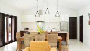 A modern kitchen with white cabinets, a central island, and hanging pendant lights. - Villa 100 - 4BR Private Villa w Private Pool - Fenced Pool (Nadi)