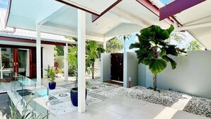 A modern outdoor patio area with a glass balustrade, a pool, and various potted plants. - Villa 100 - 4BR Private Villa w Private Pool - Fenced Pool (Nadi)