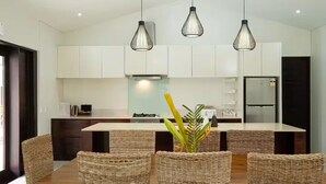 A modern kitchen with white cabinets, a central island, and three hanging pendant lights. - Villa 100 - 4BR Private Villa w Private Pool - Fenced Pool (Nadi)