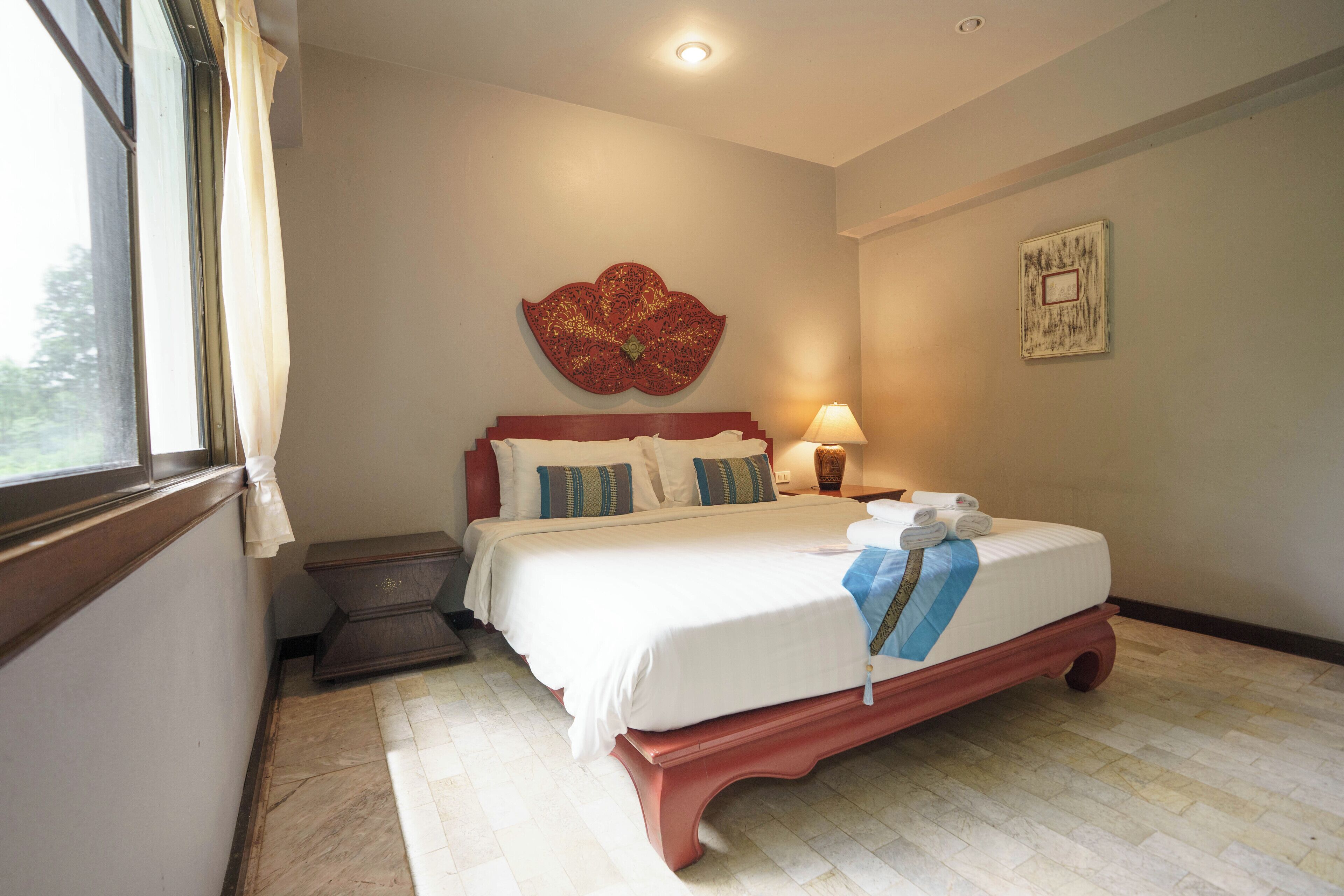 A bedroom with a bed, bedside table, lamp, and artwork on the wall.