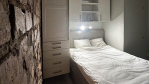 A bedroom with a bed, a wardrobe, and a brick wall. - Cozy turn-of-the-century apartment in Vasastan (Stockholms län)
