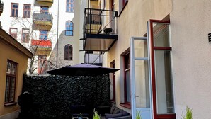 A courtyard with a stone floor, outdoor seating, and potted plants. - Cozy turn-of-the-century apartment in Vasastan (Stockholms län)