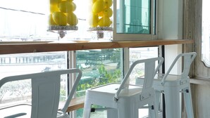 A table with two glass containers holding yellow spherical objects, white chairs, and a view of a cityscape through a large window. - Casa Ramona Boutique Rooms (Cartagena)