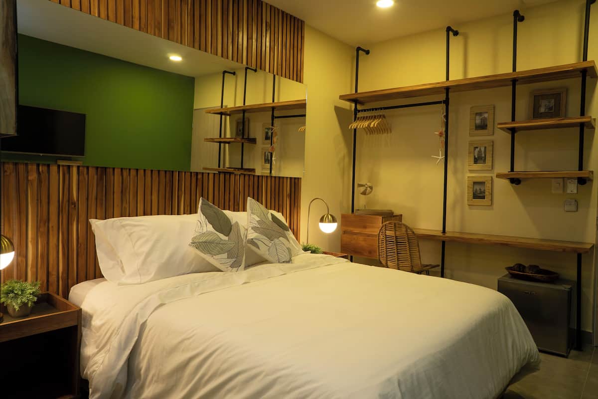 A modern bedroom with a bed, wooden paneling, a TV, and built-in shelves with pictures.