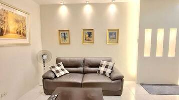 A modern living room with a leather sofa, a coffee table, and three framed pictures on the wall.